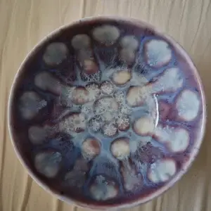 Diep bord met paars-blauw reactieglazuur in een bloemmotief